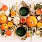 A tabletop filled with pumpkins, bowls, and leaves