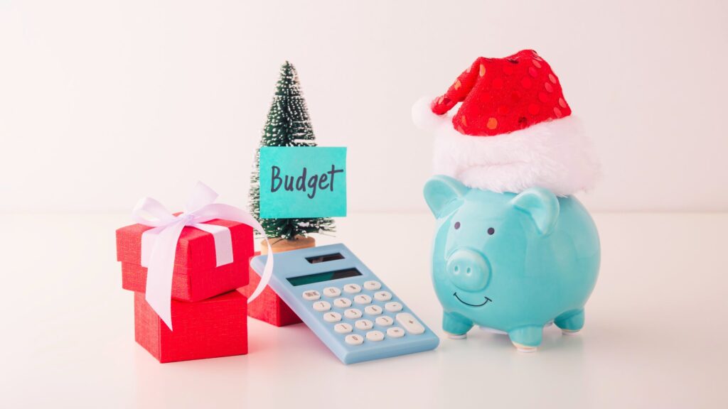 A piggy bank with a santa hat, calculator, gift, and a Christmas tree
