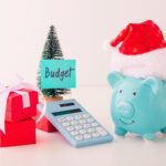 A piggy bank with a santa hat, calculator, gift, and a Christmas tree