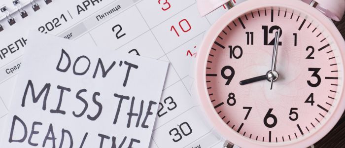 calendar with a pink alarm clock and the note: don't miss the deadline