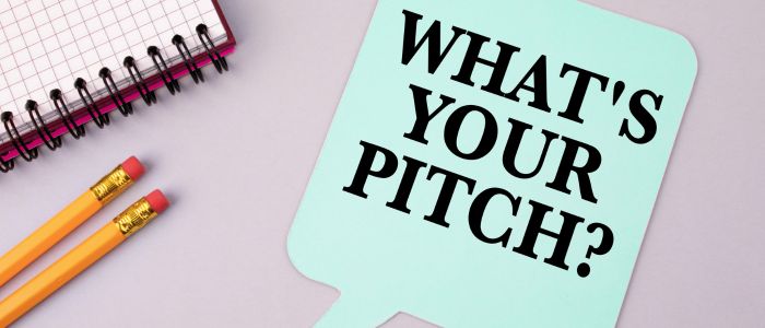 note "what's your pitch" next to a graph paper notebook and two pencils