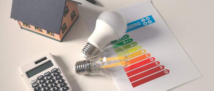 LED light bulbs, calculator, and energy efficiency chart on a desk, representing smart money-saving choices for living frugally.